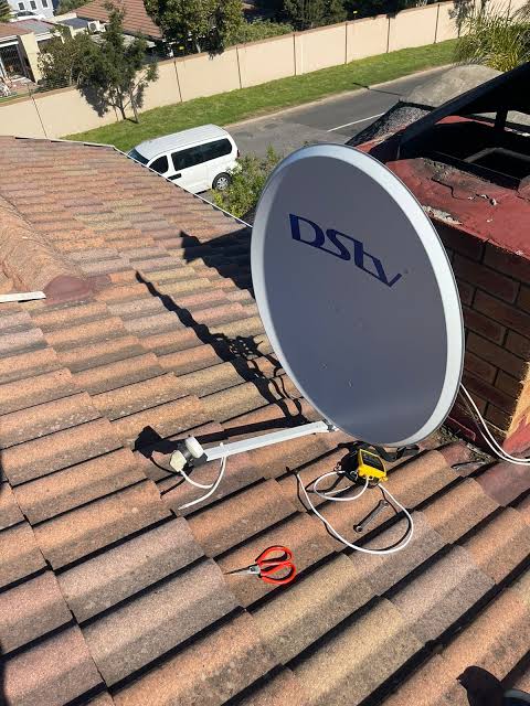 A row of satellite dishes set against an intricately tiled roof, depicting modern technology blending with traditional architecture.